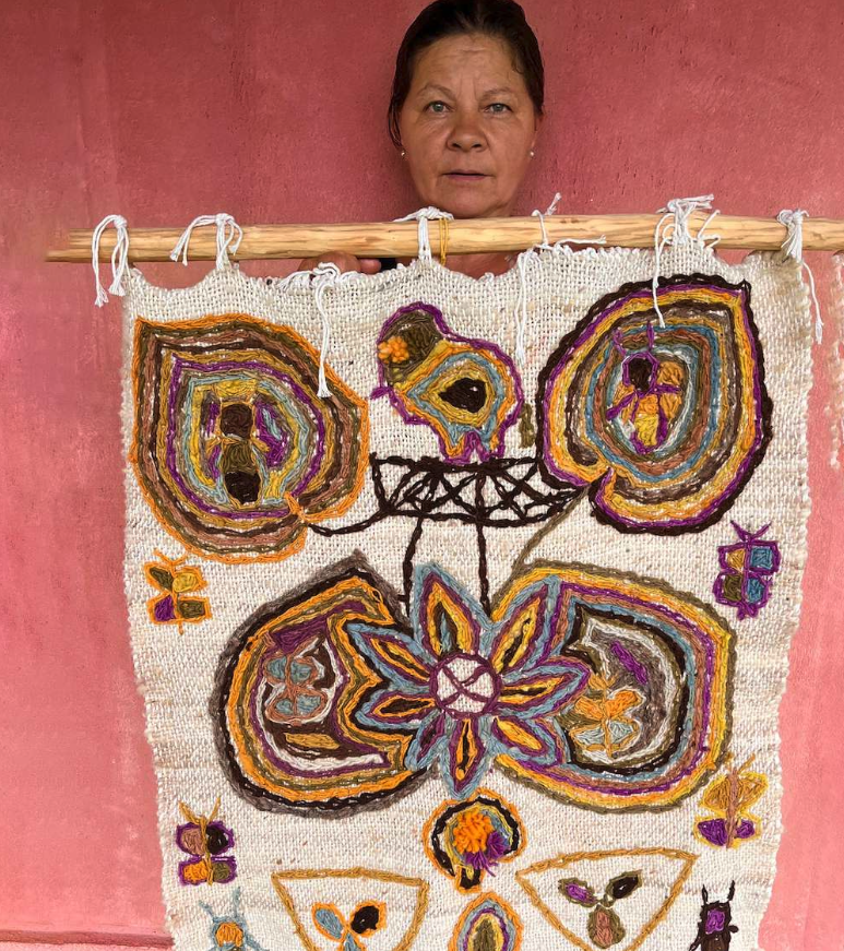 Juliana Ju mostrando uma obra de arte sua de fiação.