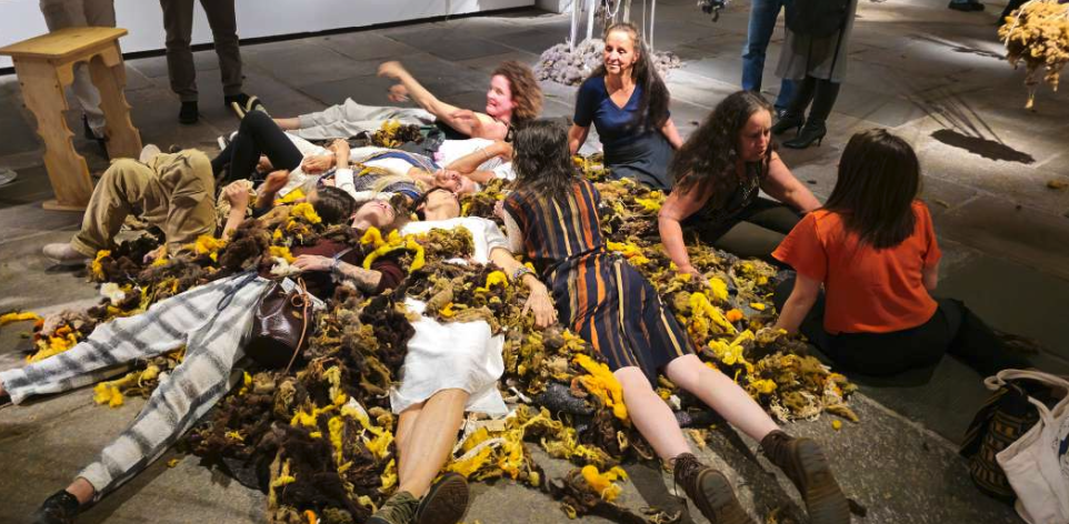 Participantes da Cooperativa da Lã Mulheres Rurais da Montanha e da VAV sobre uma escultura sensorial feita com amontoado de lã na exposição ROCADA: eclosão de desejos da Terra, Paço Imperial, Rio de Janeiro, 2025. Fotografia: arquivo VAV.